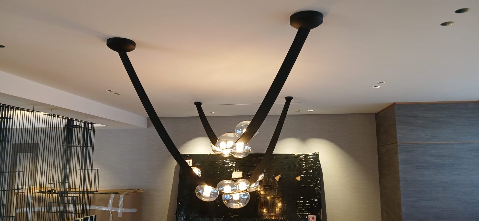 Lámpara decorativa de brazos negros y globos de cristal instalada en el techo de un salón